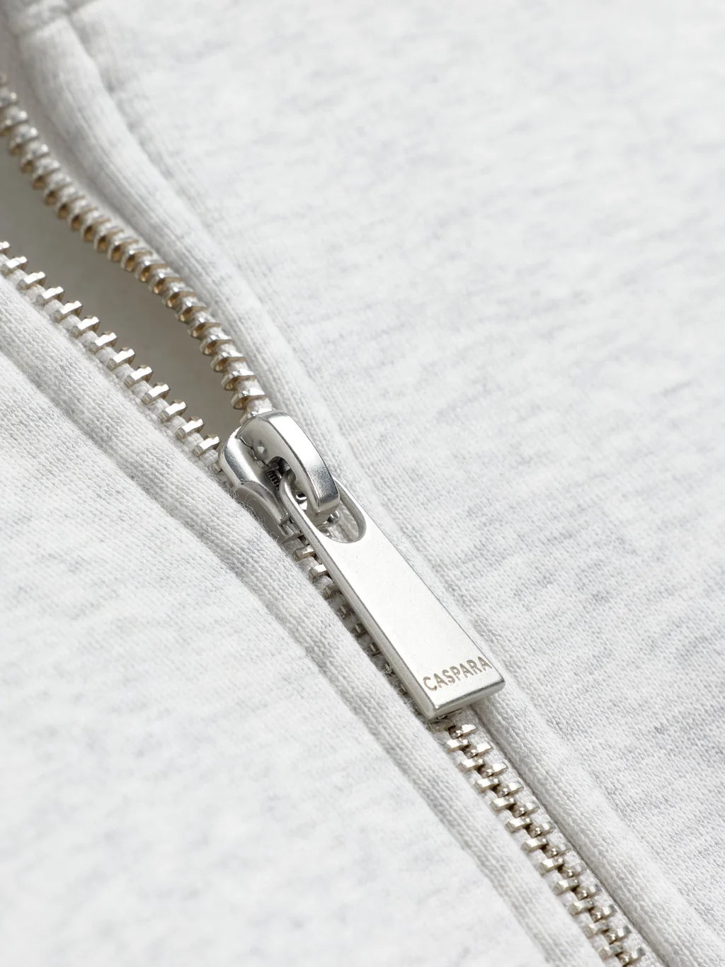Close-up of the silver engraved CASPARA zipper pull on a grey melange sweatshirt.